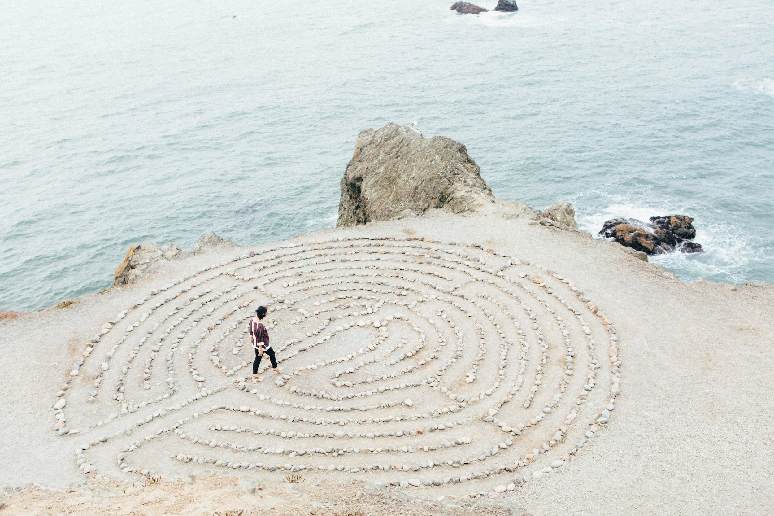 A person walking a stone labyrinth on a coastal bluff above the ocean